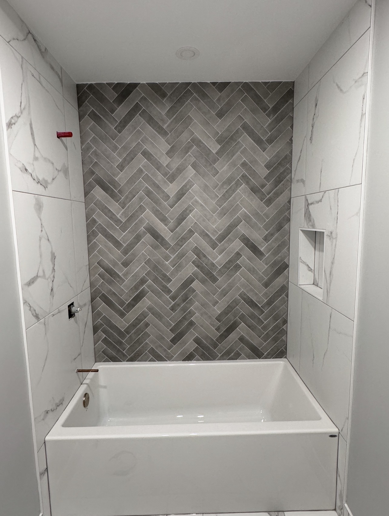 Large master ensuite renovation — floor-to-ceiling charcoal herringbone slate tile, arched window, freestanding soaker tub, walk-in shower, Orléans Ontario
