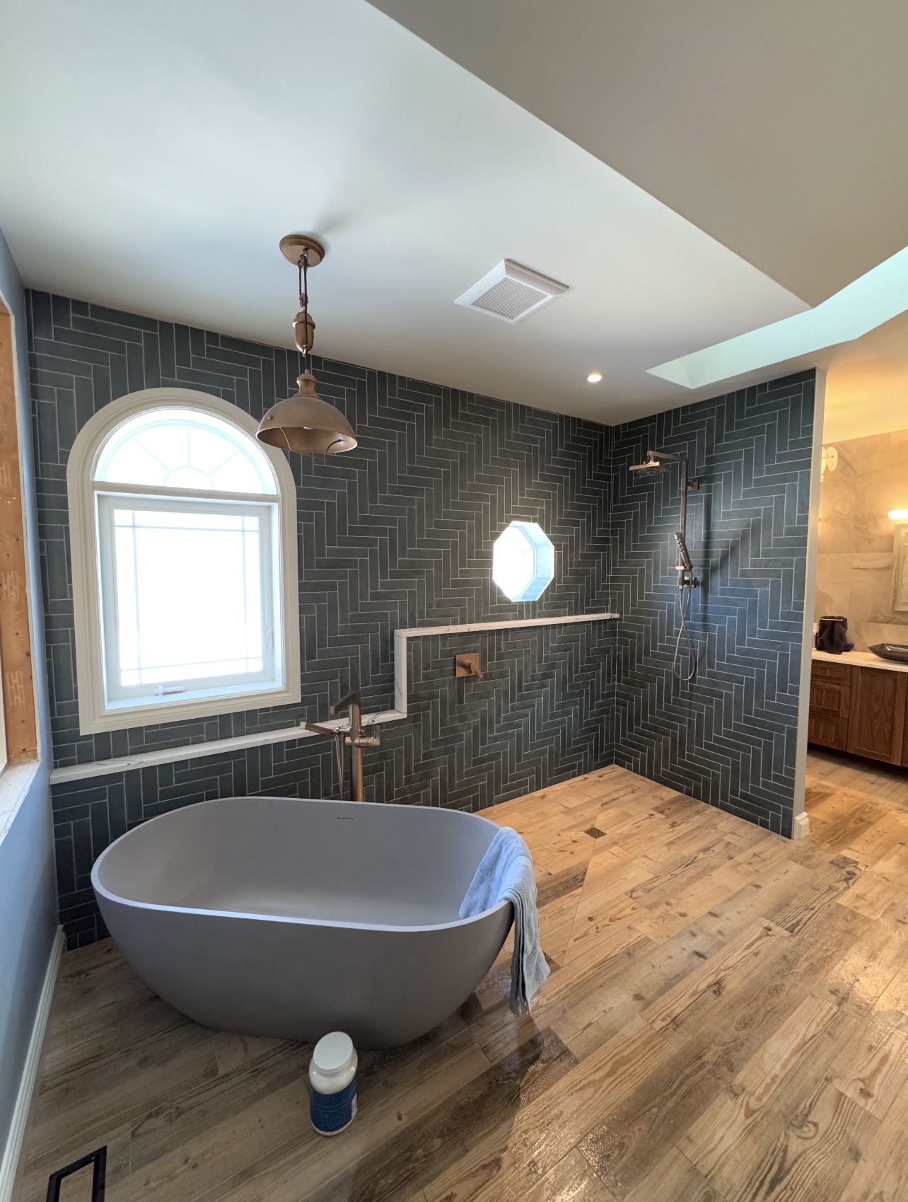 Tub surround — large format Calacatta marble porcelain with herringbone accent wall and built-in niche, custom tile installation in Orléans Ontario